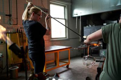 student putting glass in the glory hole